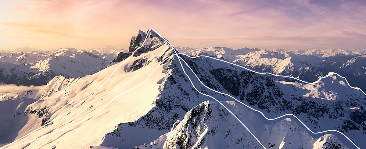 Verschneite Bergkette im Morgenlicht mit weißen Linien entlang der Gipfelgrate